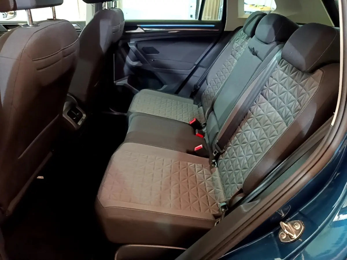 Vue latérale intérieure sur la banquette arrière grise du Volkswagen Tiguan bleu, avec motifs géométriques et ceintures visibles.