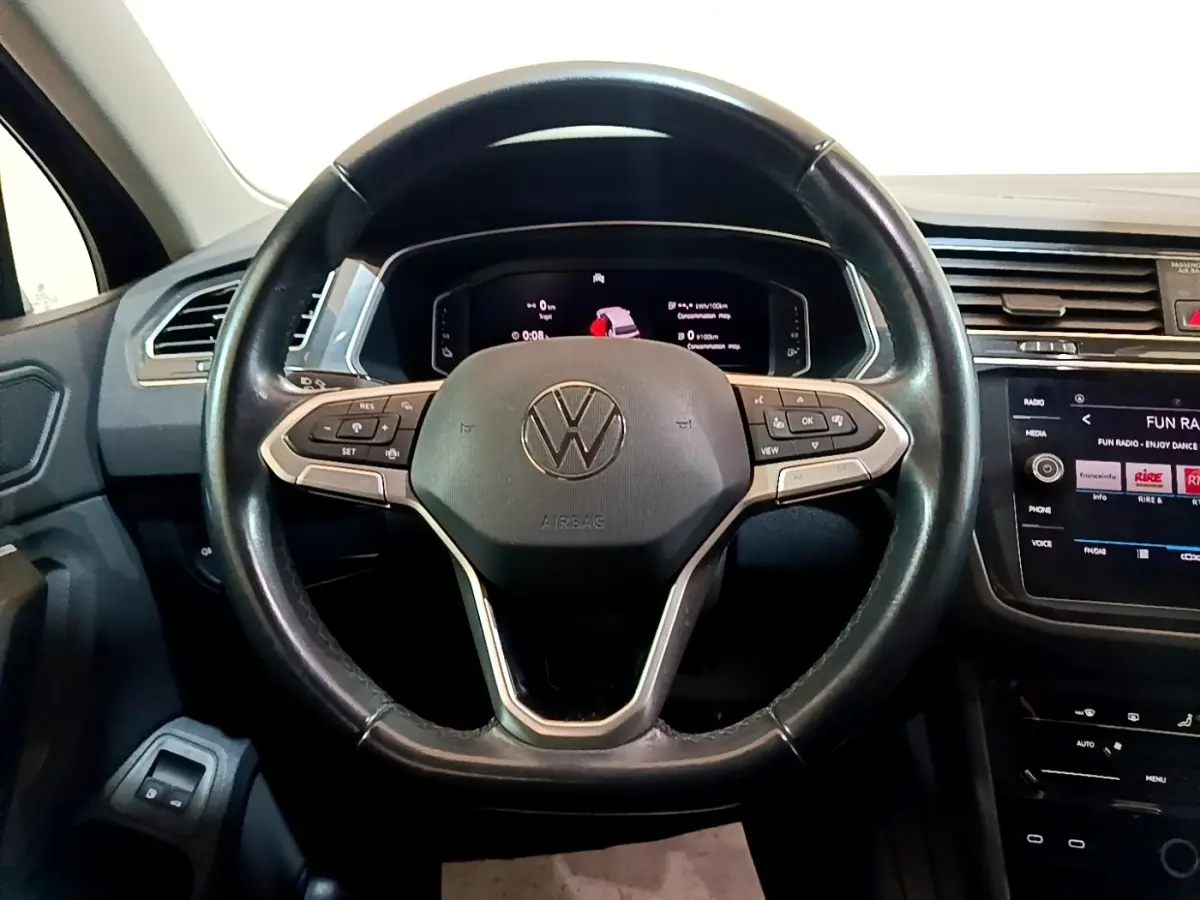 Vue rapprochée du volant cuir multifonctions et tableau de bord numérique du Volkswagen Tiguan bleu hybride rechargeable 2021.