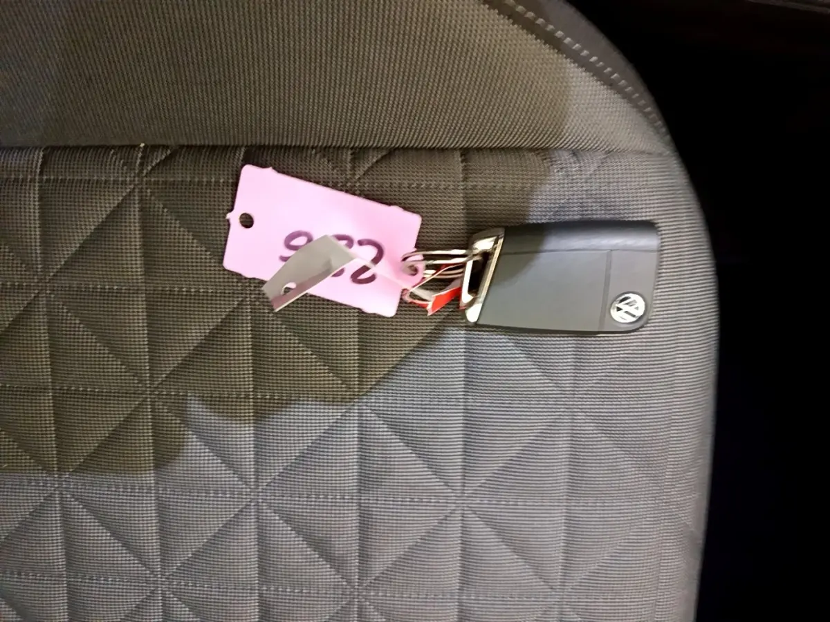 Clé Volkswagen posée sur un siège en tissu gris à motifs géométriques, intérieur du véhicule visible.