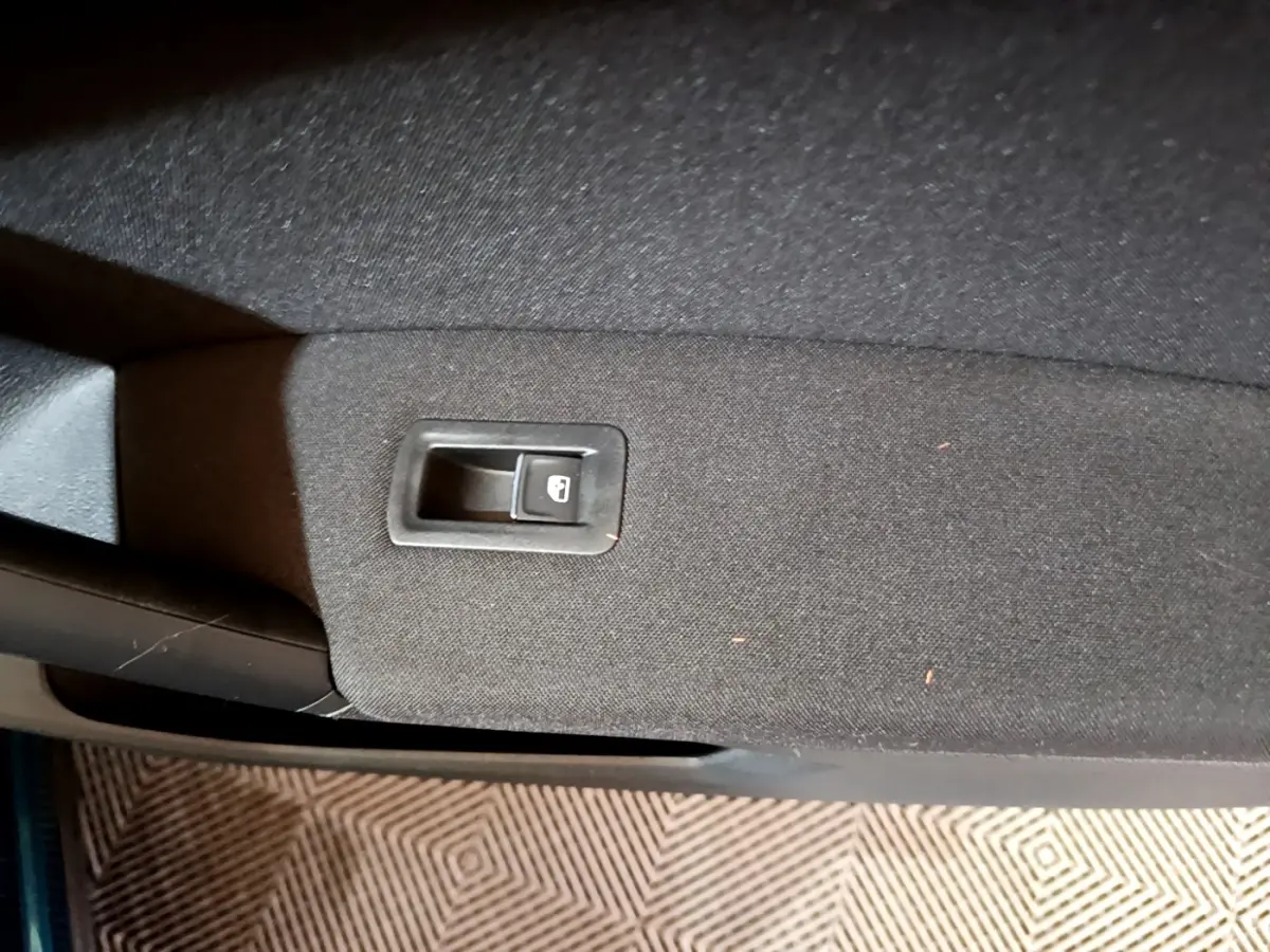 Gros plan sur la commande de verrouillage des portes intégrée dans la garniture noire d'une portière intérieure.