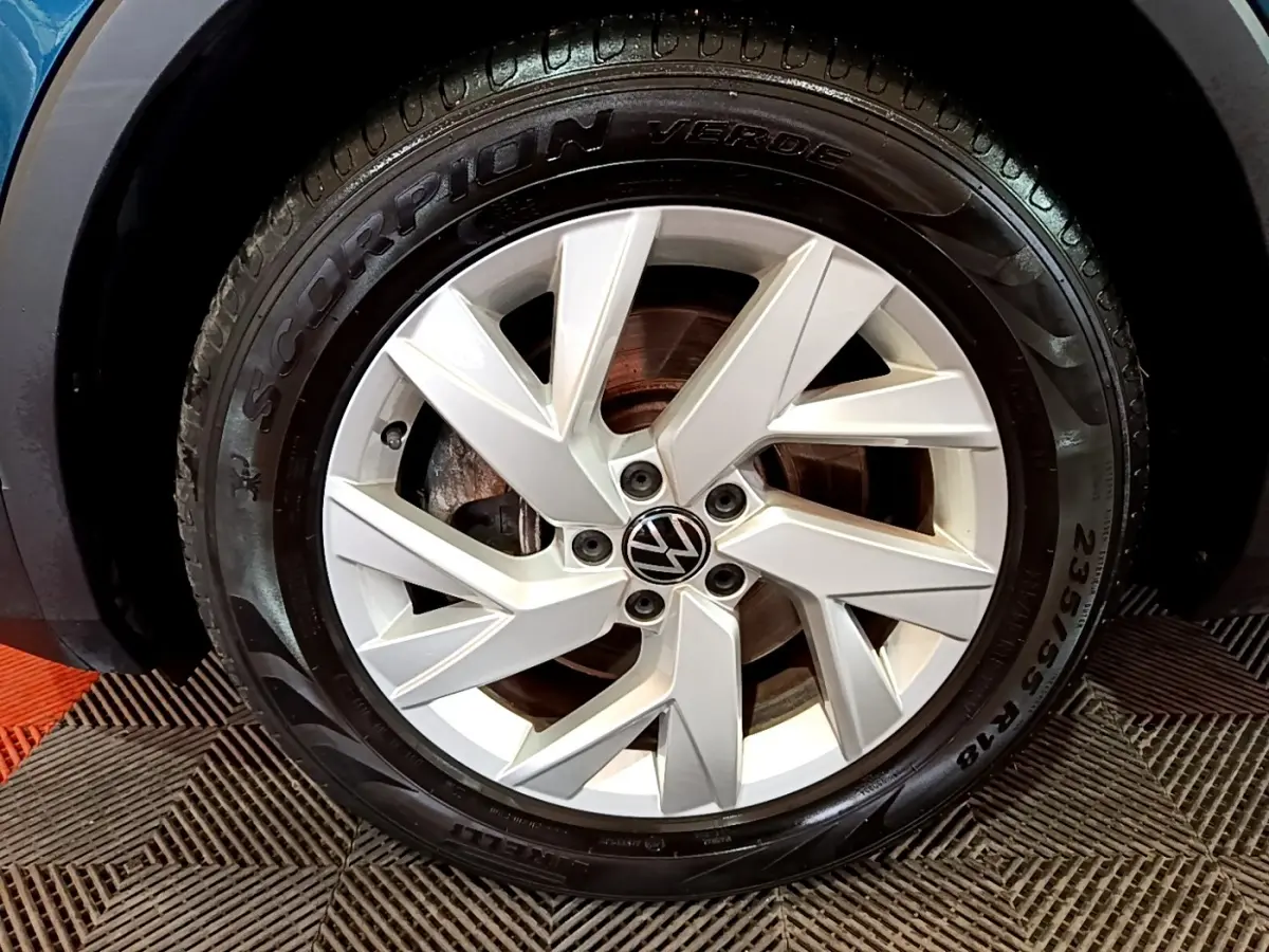 Gros plan sur la roue avant gauche du Volkswagen Tiguan bleu, mettant en valeur la jante argentée et le pneu Pirelli Scorpion Verde.