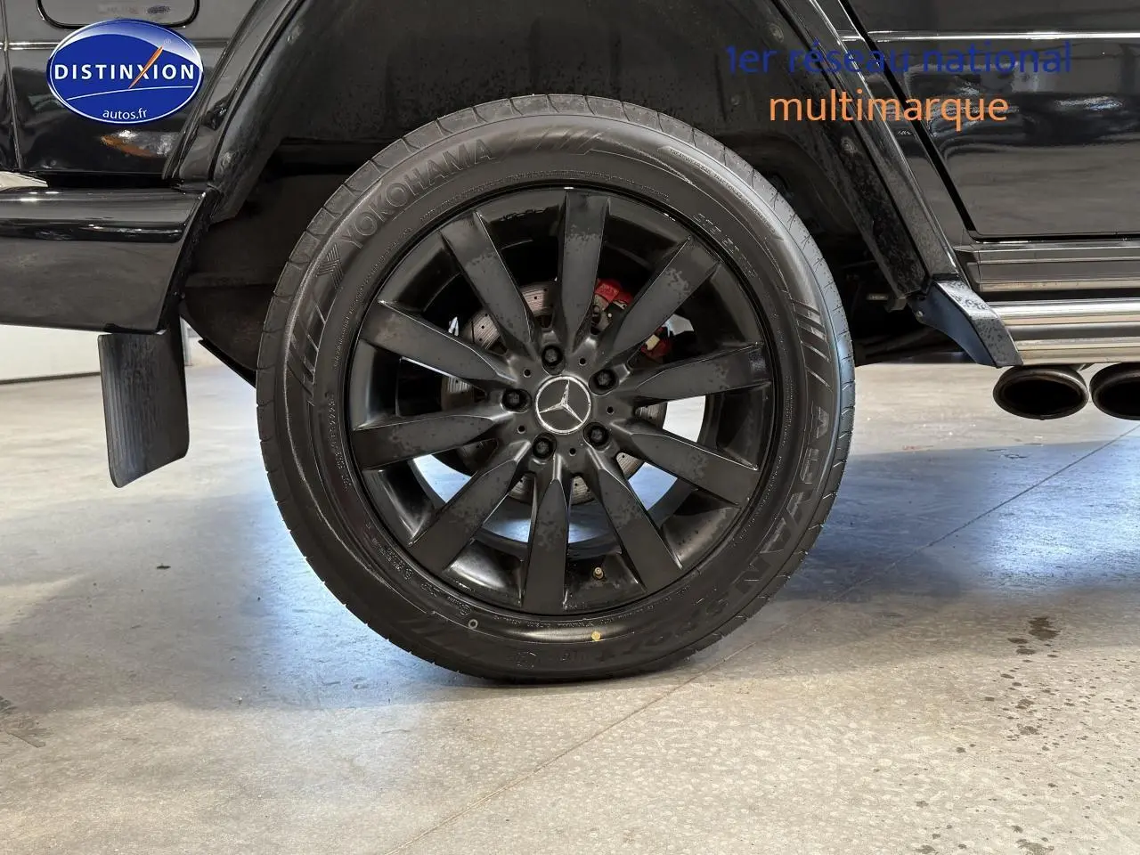 Gros plan sur la roue arrière droite noire avec jante AMG et sortie d’échappement chromée d’un Mercedes Classe G 2014.