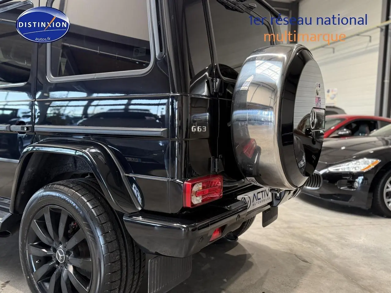 Vue 3/4 arrière droite d'un Mercedes Classe G 63 AMG noir avec roue de secours chromée et jantes noires.