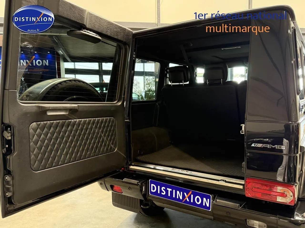 Vue arrière gauche d'un Mercedes Classe G 5.5 63 AMG noir avec porte arrière ouverte dévoilant le coffre spacieux.