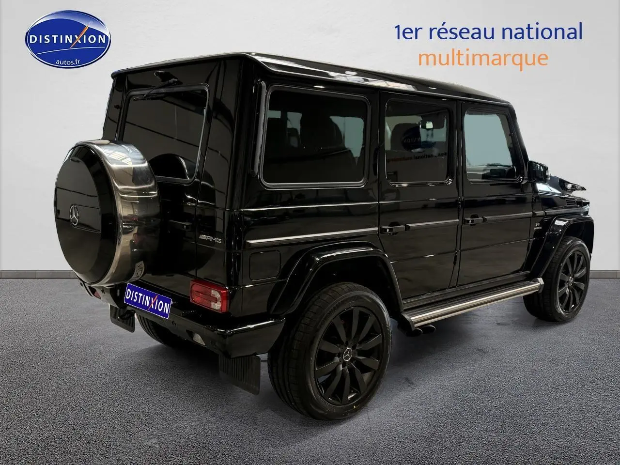 Vue 3/4 arrière droite d'un Mercedes Classe G 5.5 63 AMG noir avec roue de secours chromée et jantes noires.