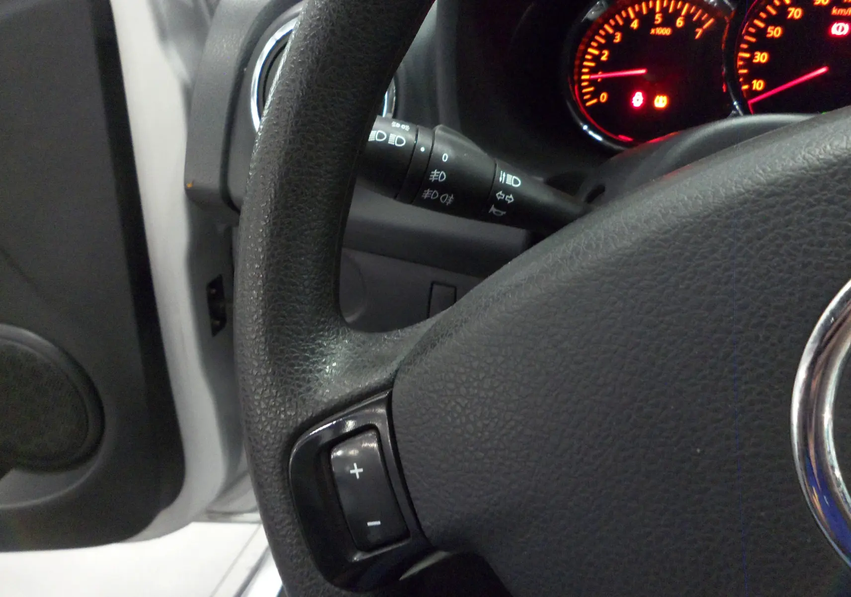 Gros plan sur le volant noir et le tableau de bord éclairé en rouge d'une Dacia Sandero Stepway Gris Platine 2016.