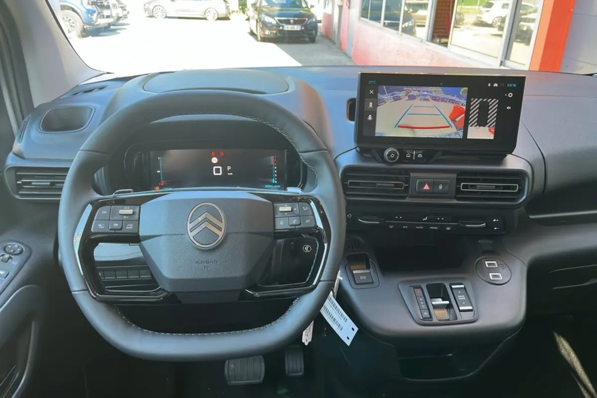 Intérieur du Citroën Berlingo 2025, vue du poste de conduite avec volant multifonctions et écran tactile affichant la caméra de recul.