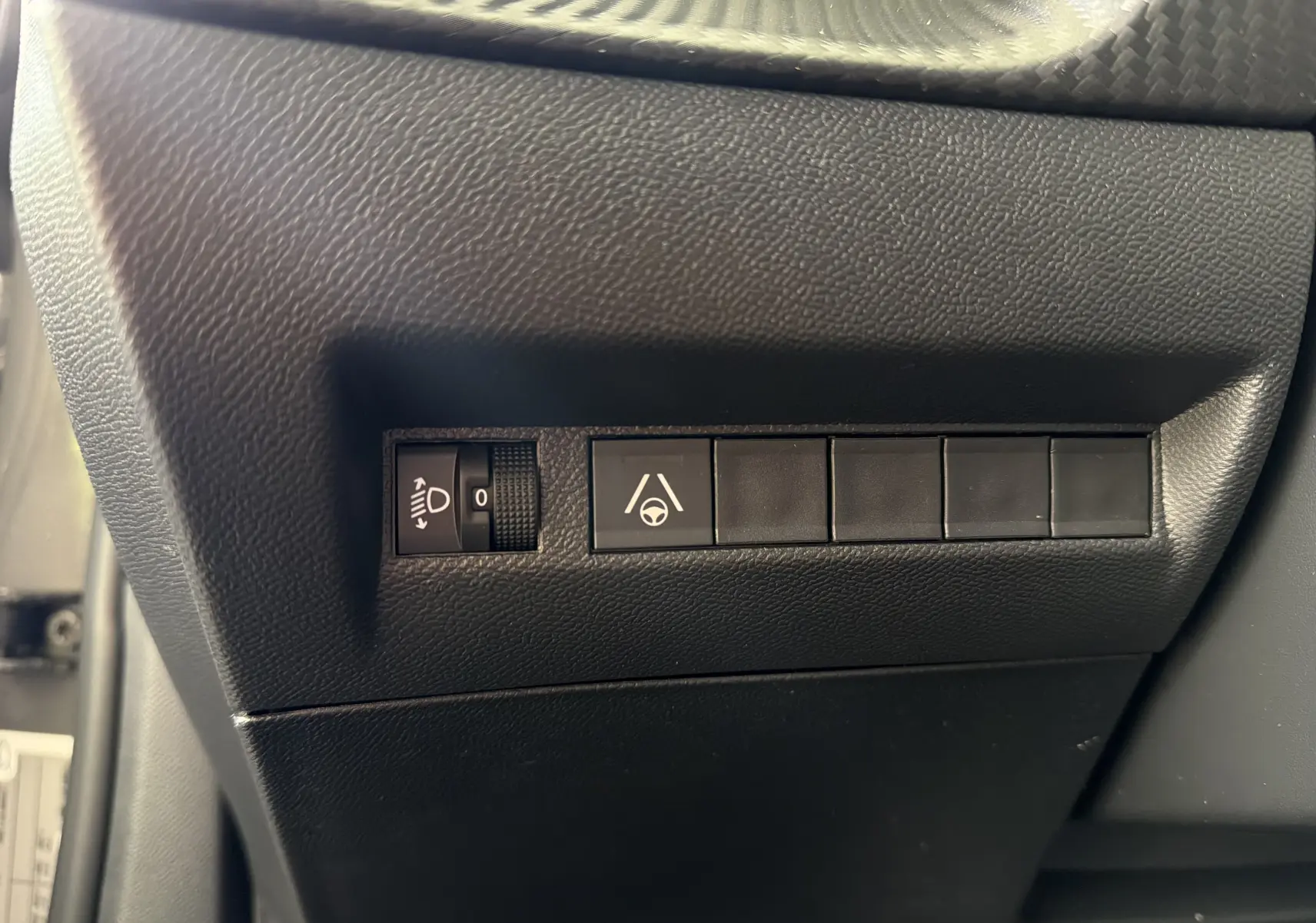 Gros plan sur les commandes noires du tableau de bord côté gauche dans un Peugeot 2008 gris Sellenium 2023.
