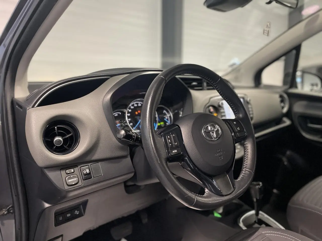 Intérieur de la Toyota Yaris hybride 2020 vu côté gauche, volant cuir noir et tableau de bord gris clair.
