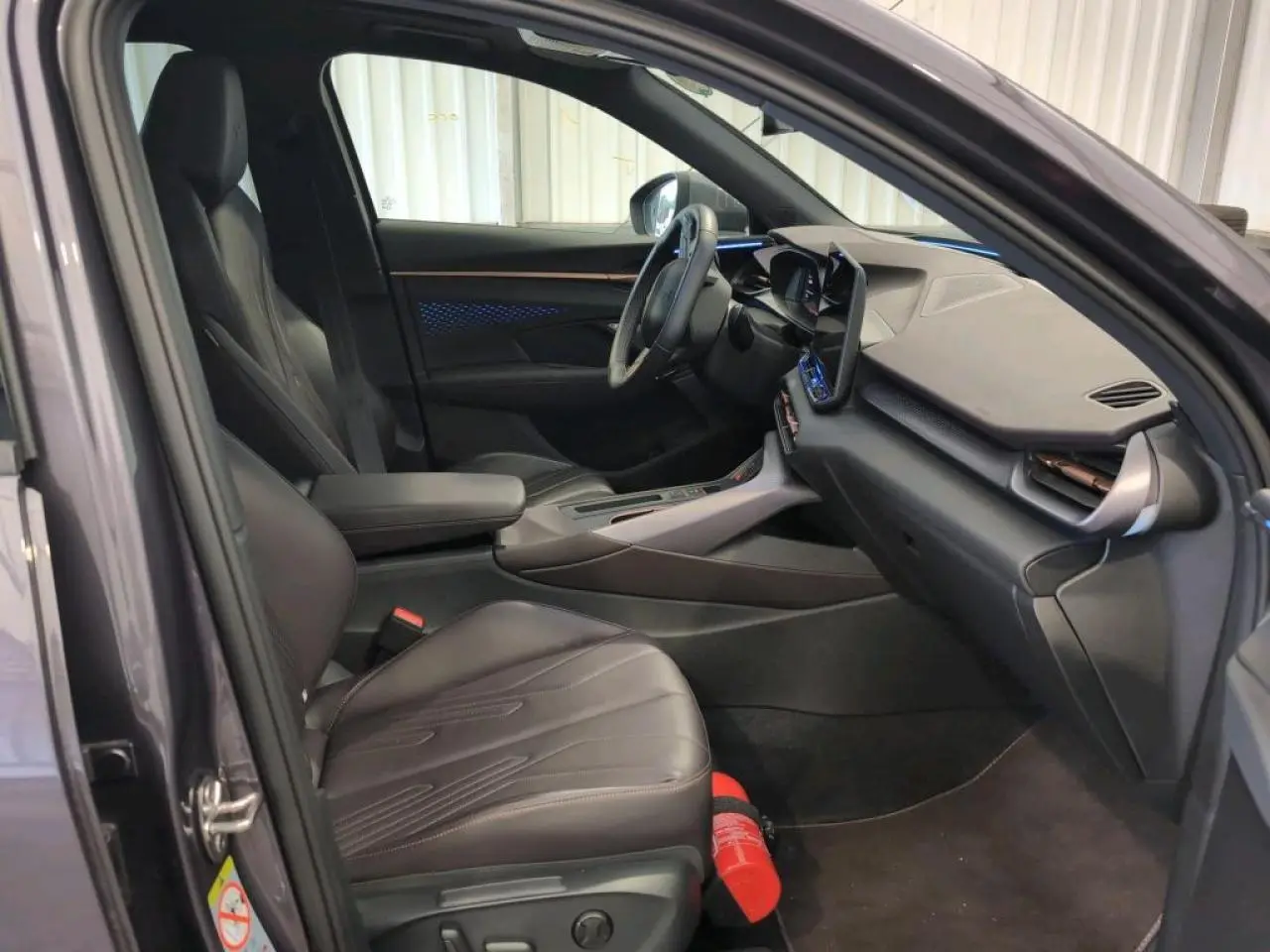 Intérieur avant du CUPRA TERRAMAR 2024 en cuir noir avec tableau de bord texturé et éclairage d'ambiance bleu visible.