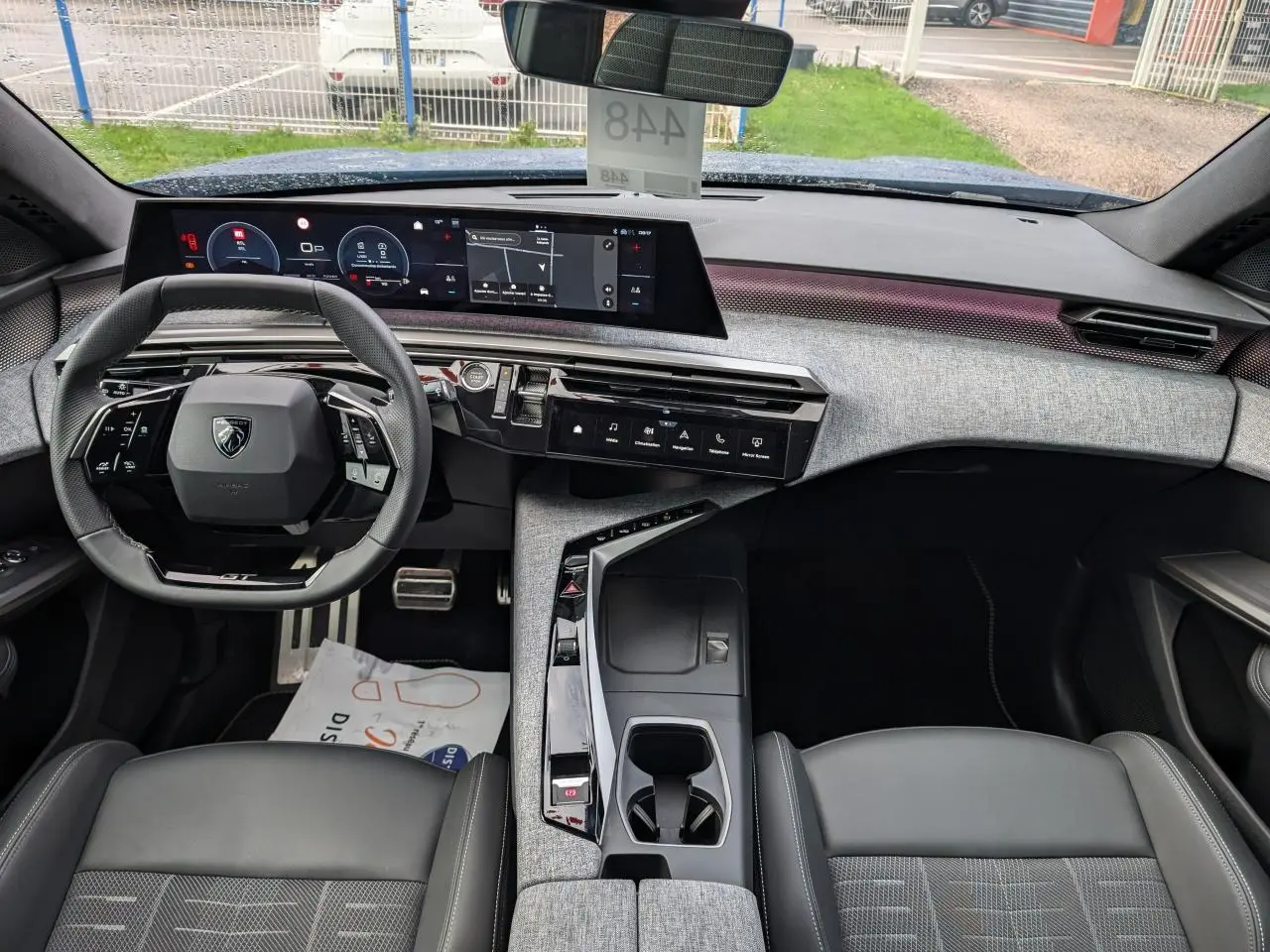 Vue intérieure avant du Peugeot 3008 2025 hybride, avec tableau de bord numérique panoramique et sellerie tissu gris.