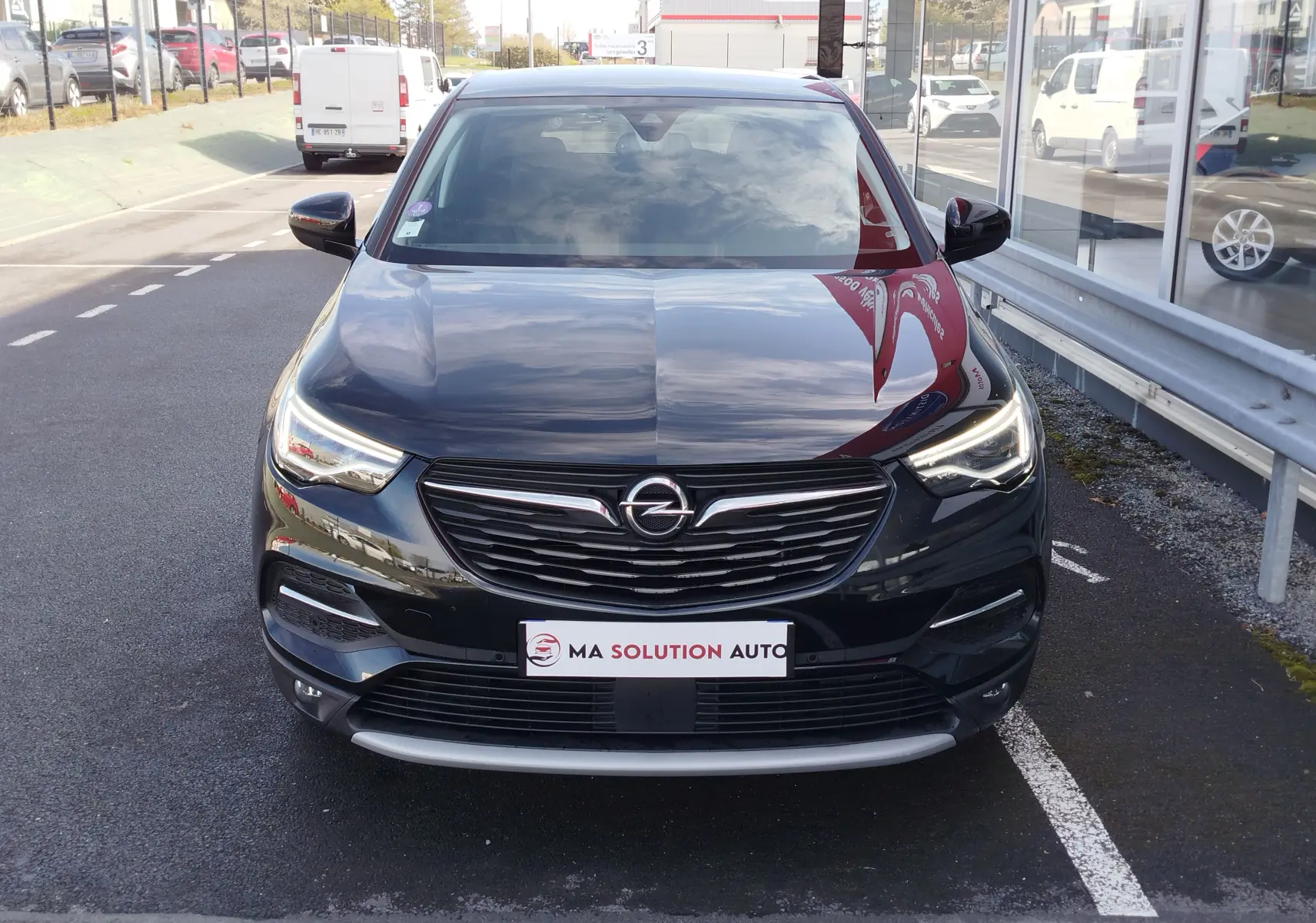 Vue frontale d'un Opel Grandland X noir diamant 2021 avec calandre chromée et phares LED allumés.