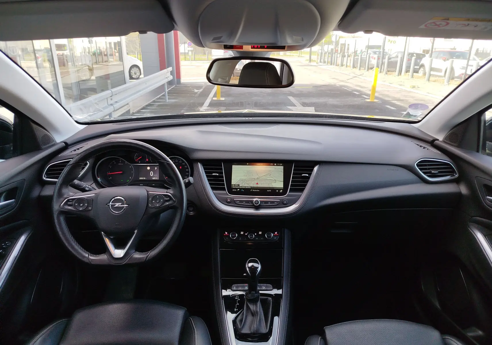 Vue intérieure frontale du tableau de bord noir de l'Opel Grandland X 1.6 Turbo avec écran central et volant multifonction.