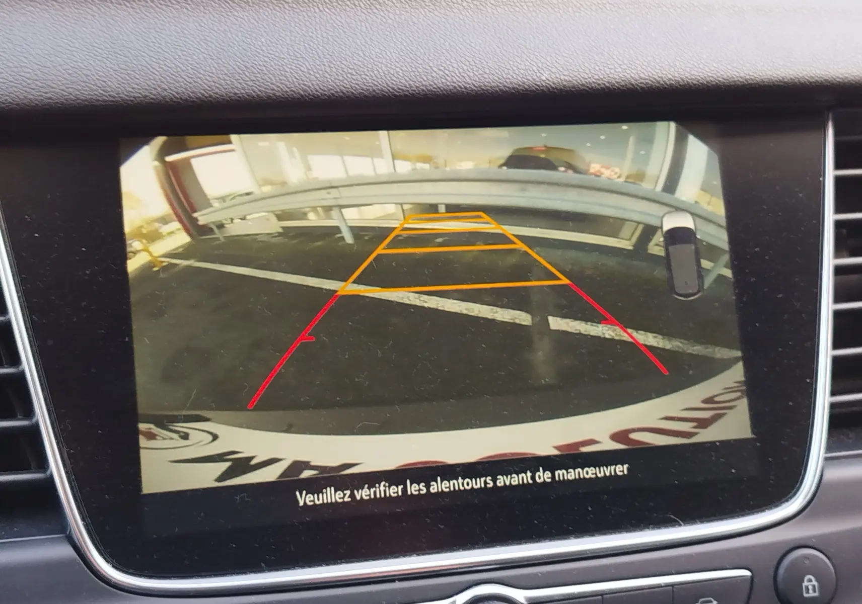 Vue de l'écran de recul de l'Opel Grandland X noir diamant, affichant les lignes de guidage orange et rouge sur le parking.