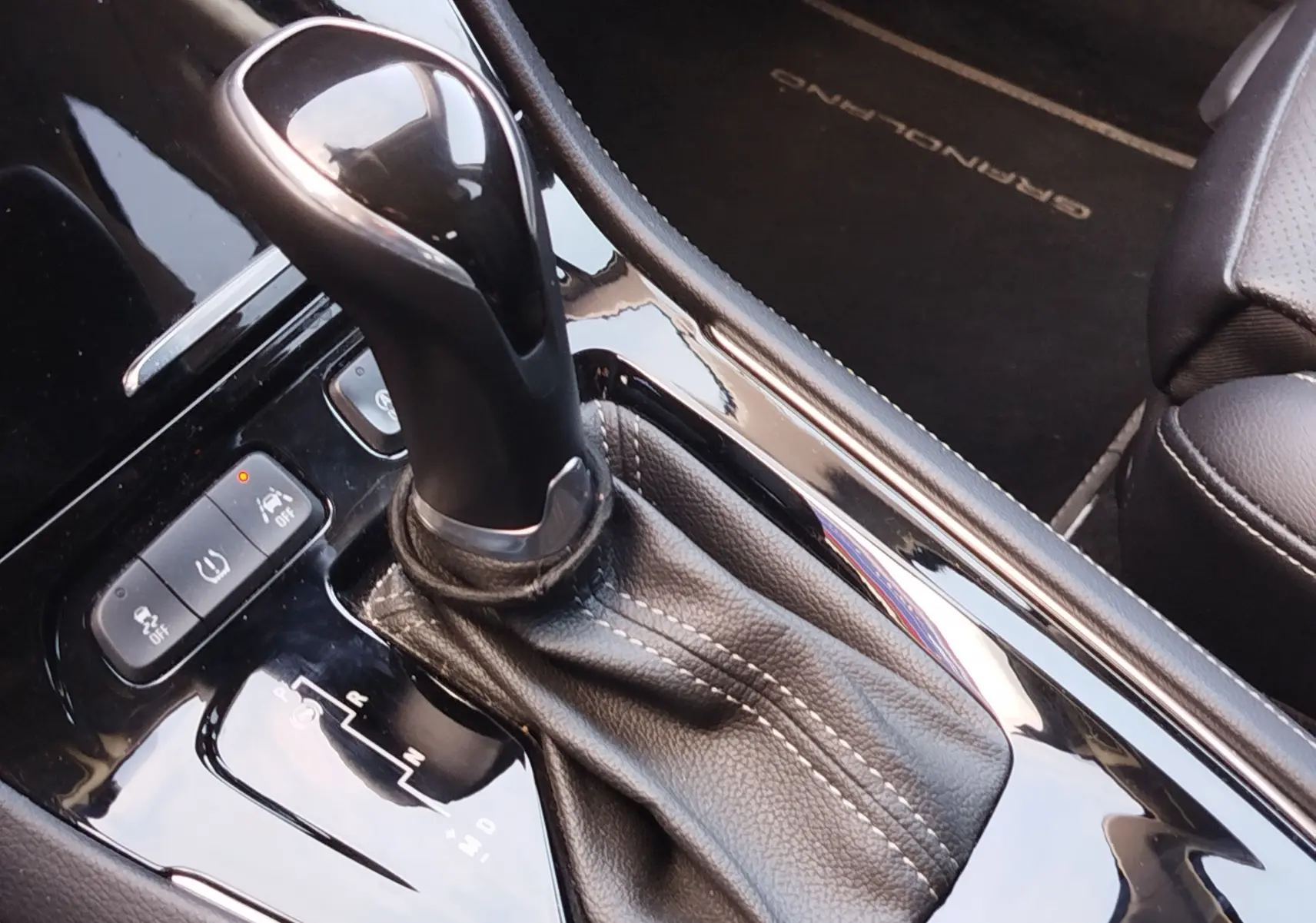 Gros plan sur le levier de vitesse automatique noir brillant de l’Opel Grandland X 1.6 Turbo, avec console en cuir noir et tapis marqué Grandland.
