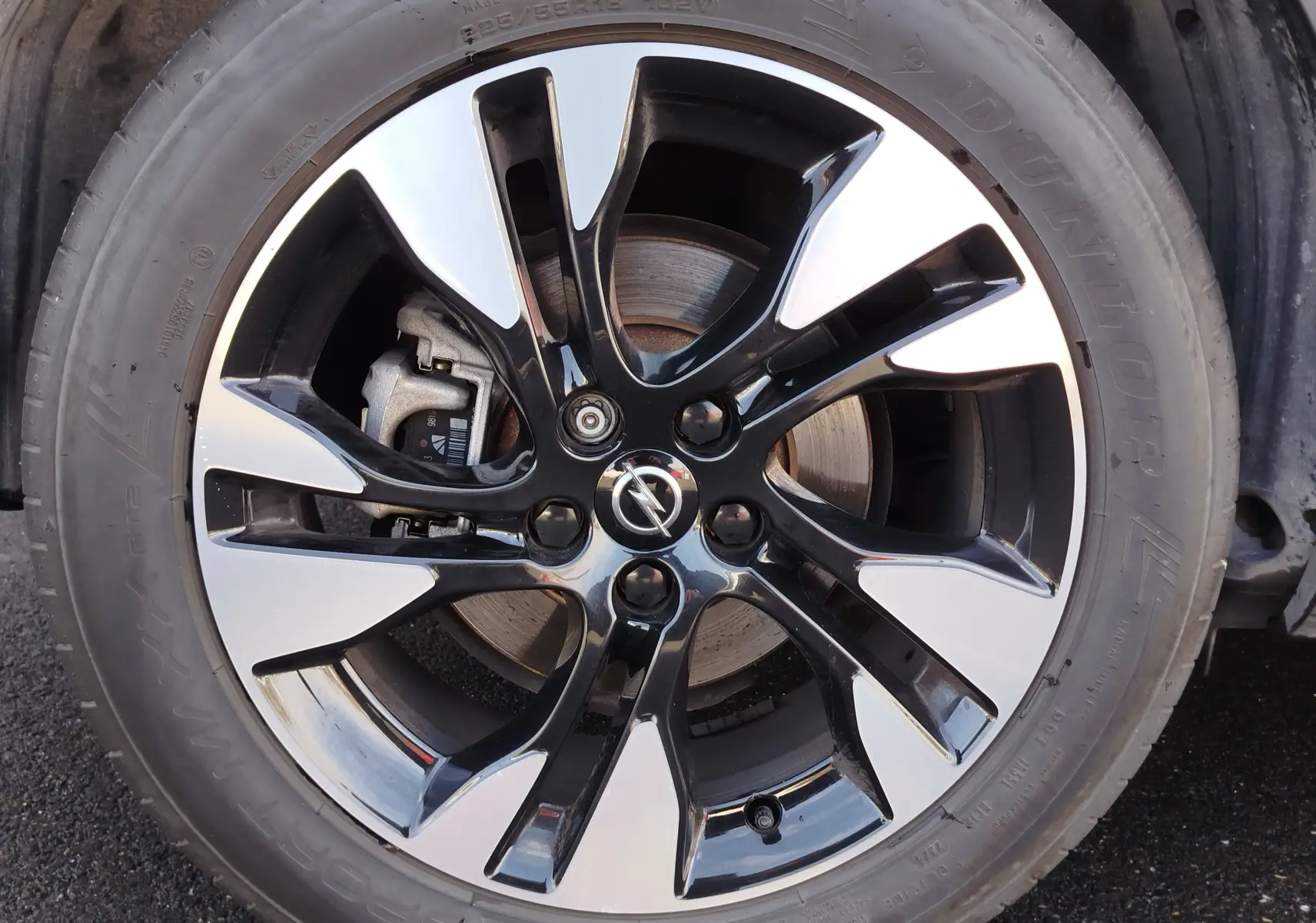 Gros plan sur la jante bi-ton noire et argentée avec logo Opel, montée sur un pneu Dunlop du Grandland X noir diamant.