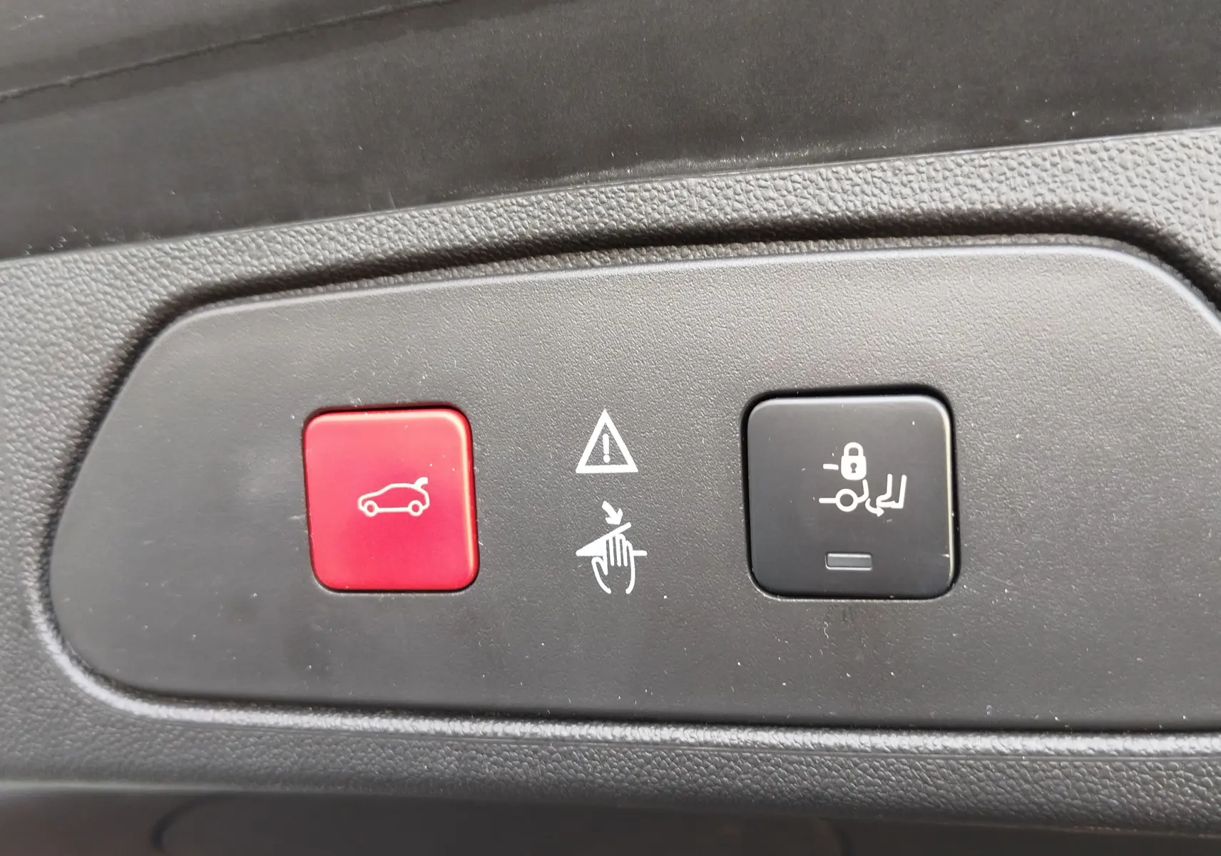 Gros plan sur les boutons de commande du hayon et du verrouillage des sièges arrière dans un Opel Grandland X noir.