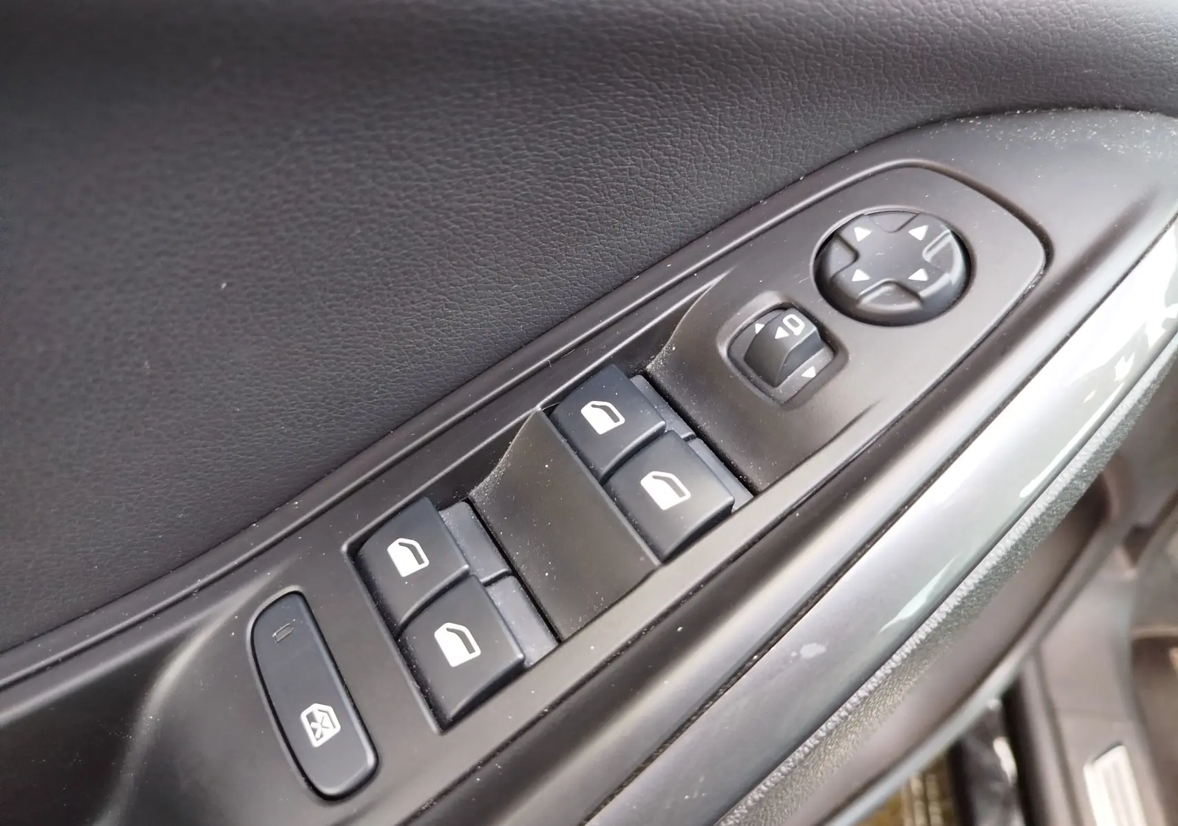 Gros plan sur les commandes de lève-vitres et réglages des rétroviseurs côté conducteur d’un Opel Grandland X noir.