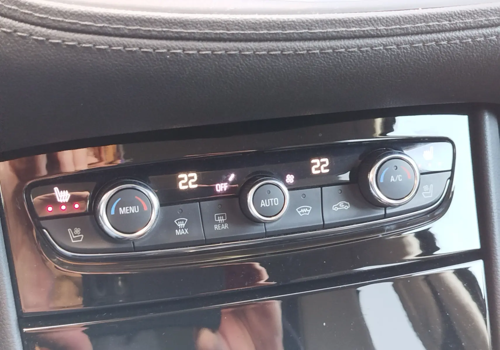 Vue rapprochée du panneau de commande de la climatisation automatique du Opel Grandland X noir, avec réglages à 22°C et sièges chauffants activés.