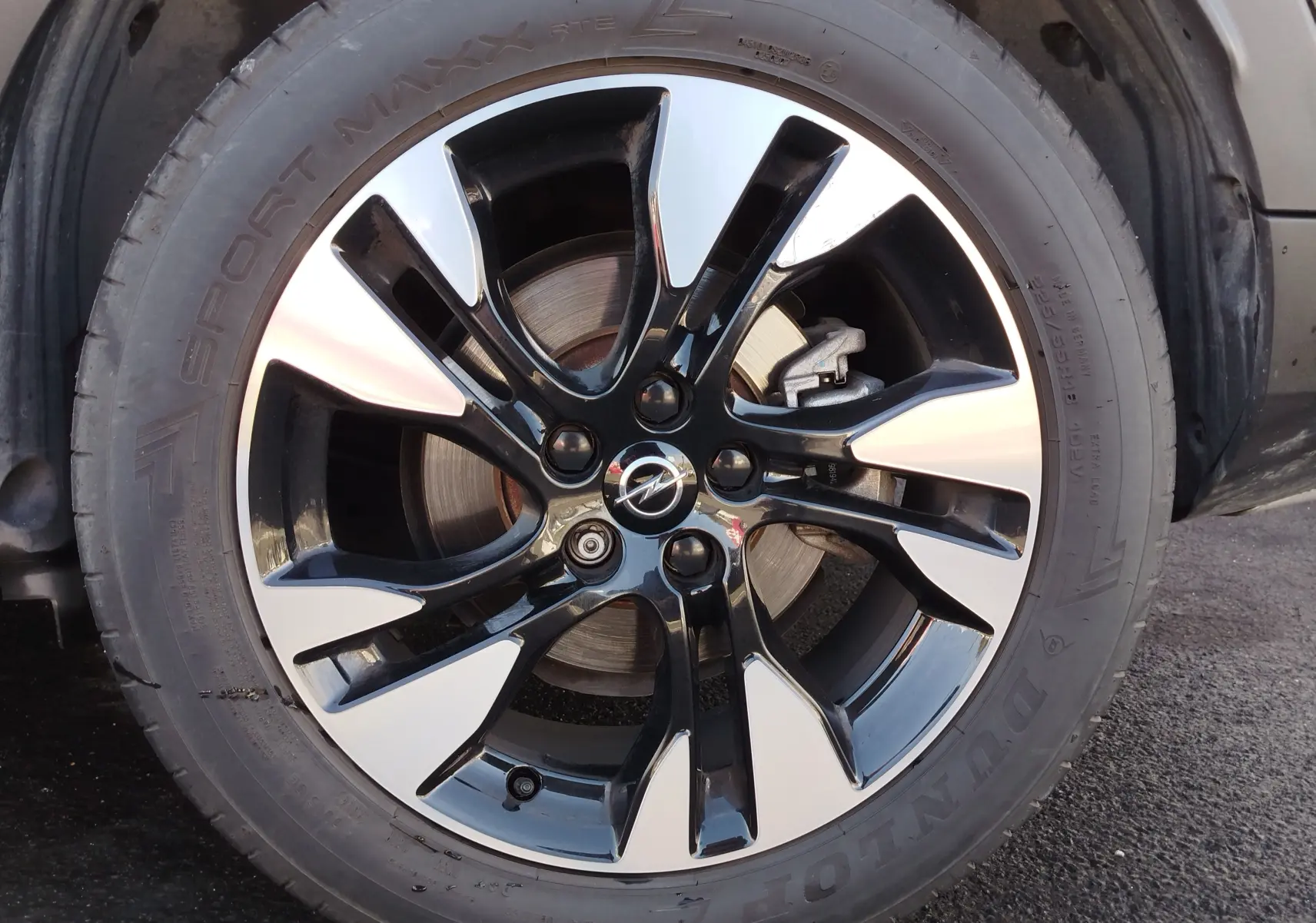 Gros plan sur la jante bi-ton noire et argentée avec logo Opel, montée sur un pneu Dunlop Sport Maxx.