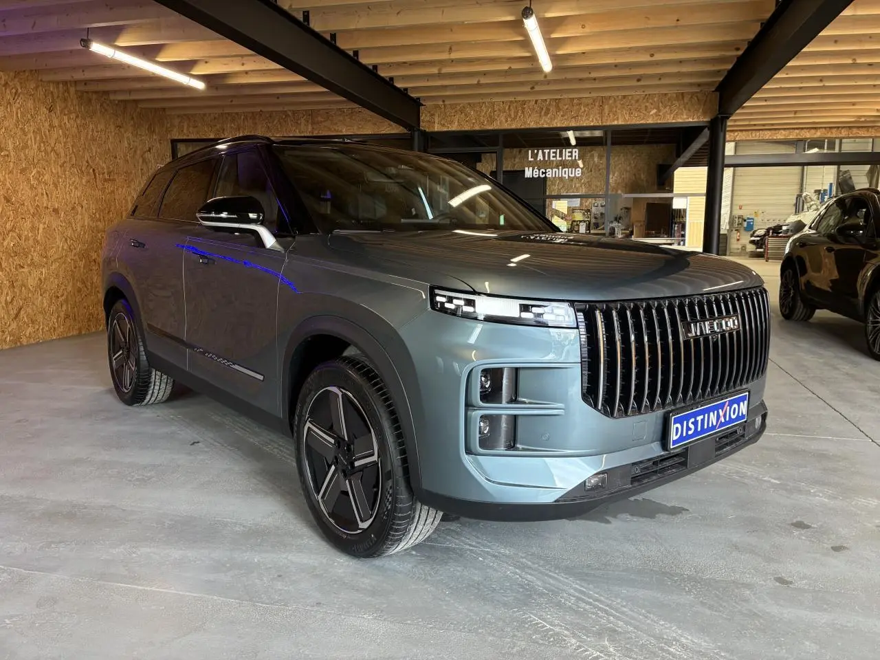 SUV JAECOO J7 gris olive en 3/4 avant droit, avec calandre verticale noire et jantes alliage 19 pouces.
