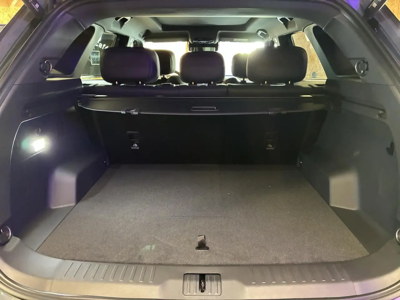 Coffre ouvert vu de l'arrière du JAECOO J7 gris olive, intérieur noir et banquette arrière visible.