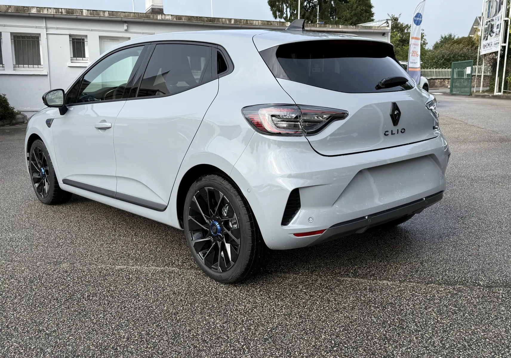 Vue 3/4 arrière droite d'une Renault Clio V gris Rafale 2025 avec jantes noires et vitres teintées.