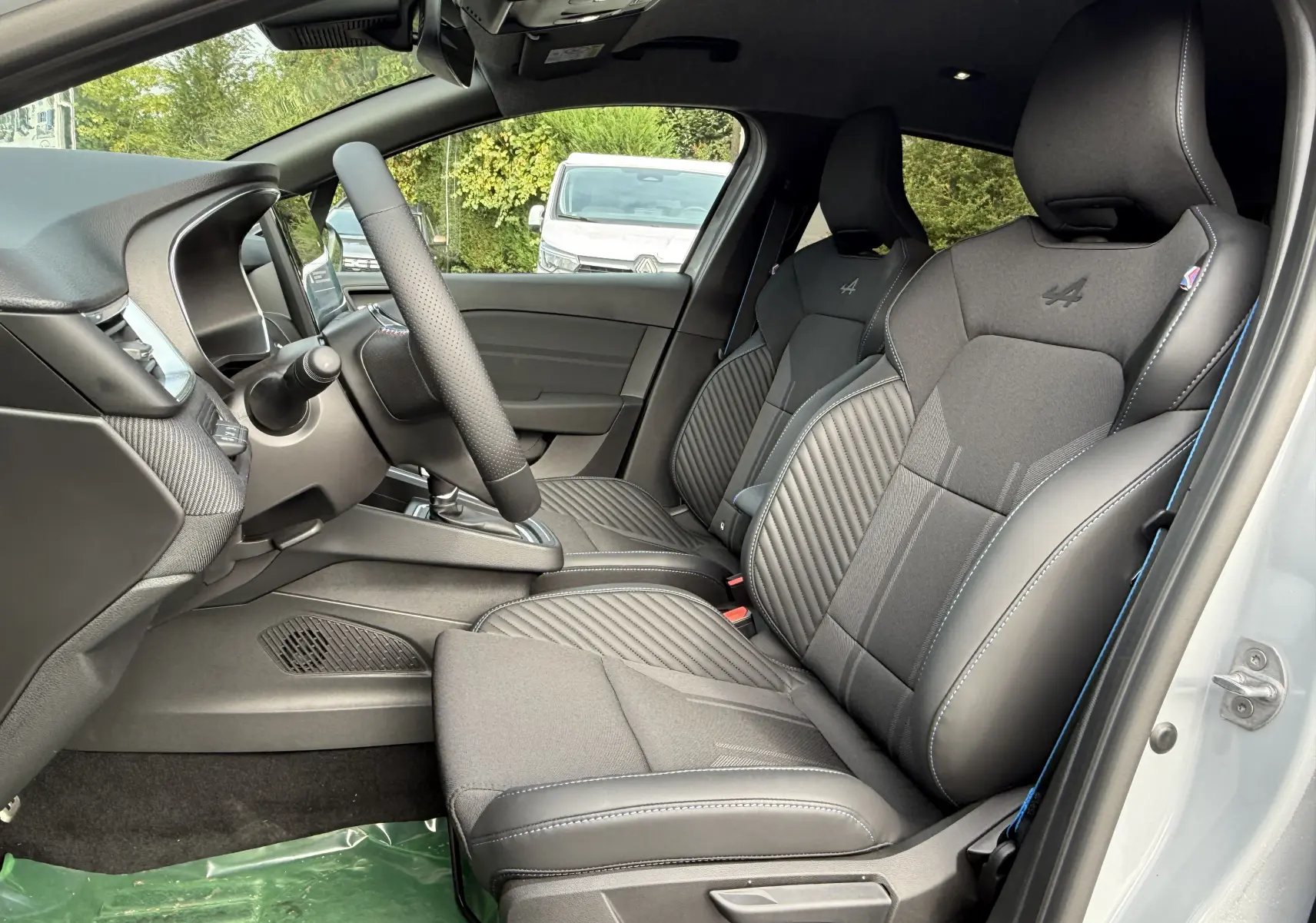 Intérieur de la Renault Clio V hybride 2025, vue côté gauche sur les sièges gris avec logo Alpine brodé.