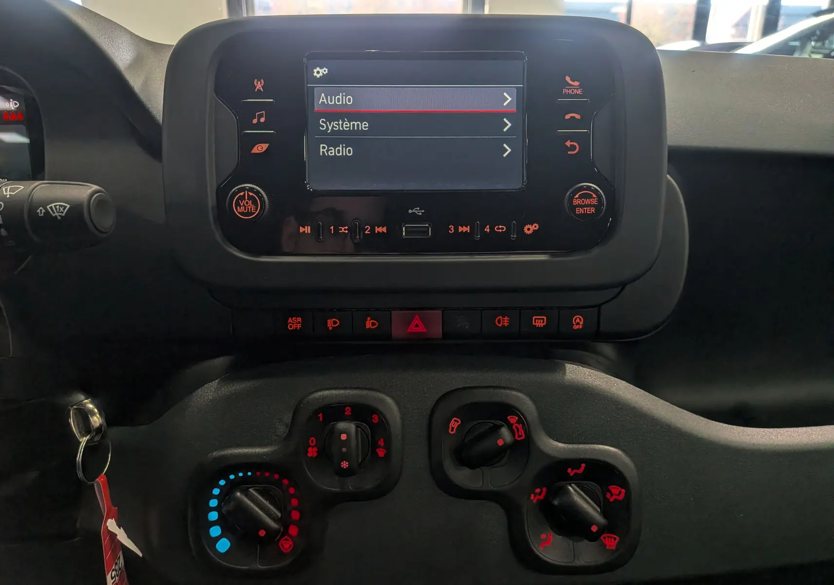 Vue rapprochée du tableau de bord et de l’écran multimédia de la Fiat Panda 1.0 Hybrid 2025 avec commandes climatiques manuelles.
