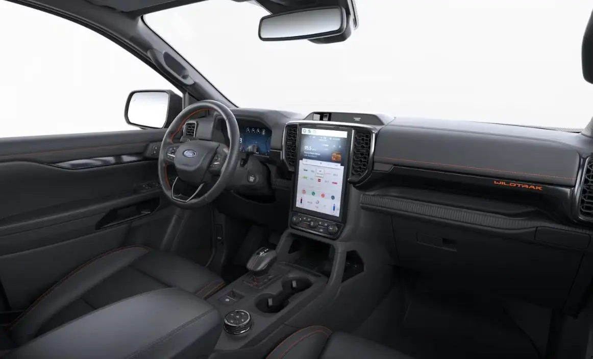 Vue intérieure côté conducteur du Ford Ranger Wildtrak 2025, tableau de bord noir avec surpiqûres orange et écran tactile vertical.