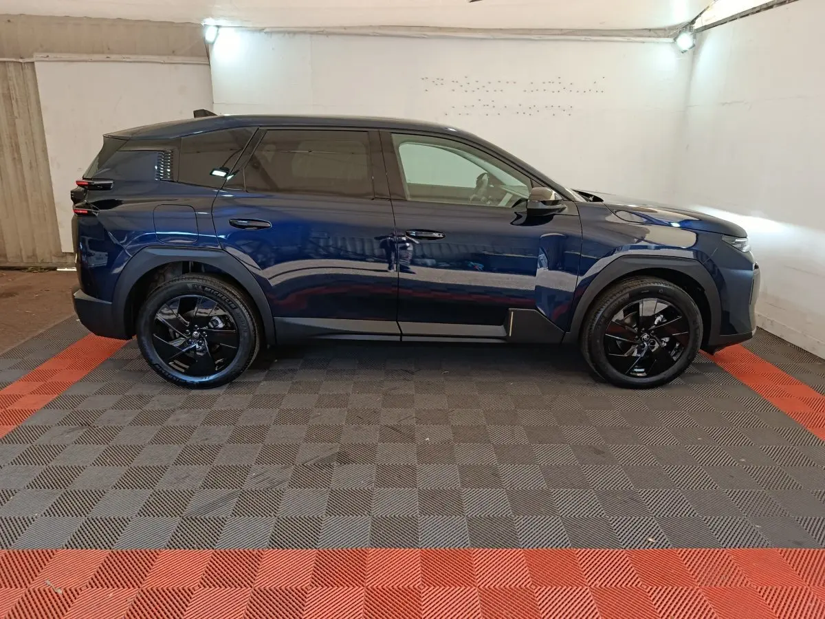 Vue latérale droite d'une Citroën C5 hybride bleu foncé avec jantes noires dans un garage éclairé.