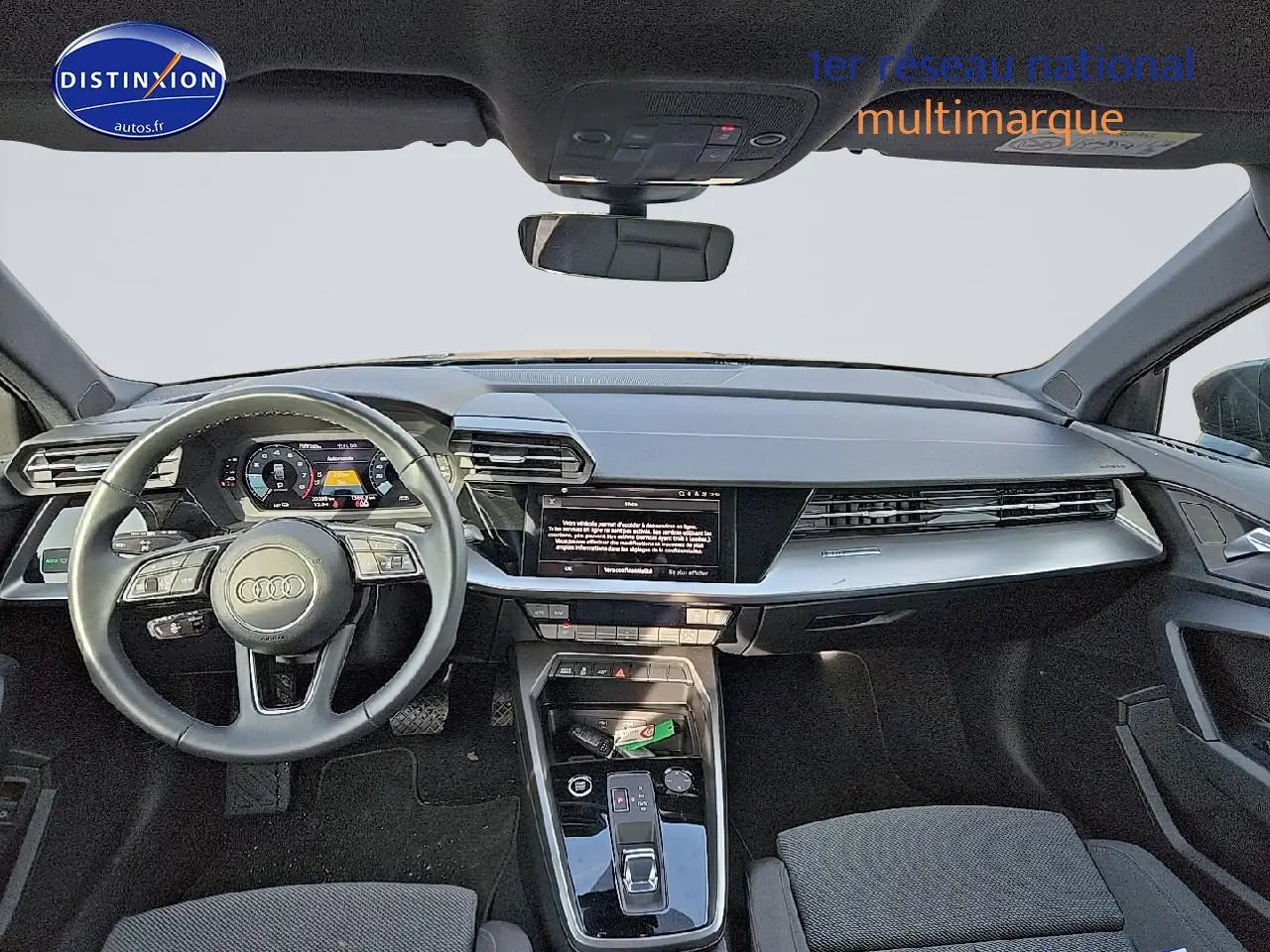 Vue frontale de l'intérieur de l'Audi A3 Sportback 45 TFSI e 2024 avec tableau de bord et volant cuir noir.