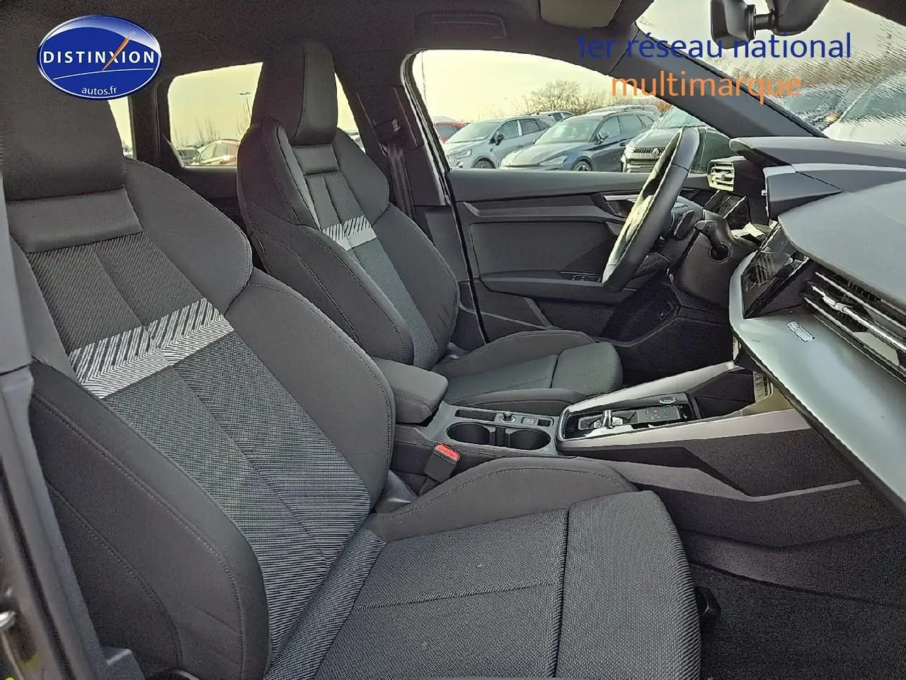 Intérieur Audi A3 Sportback 2024 vu côté conducteur, sièges sport noirs avec motifs gris et console centrale moderne.