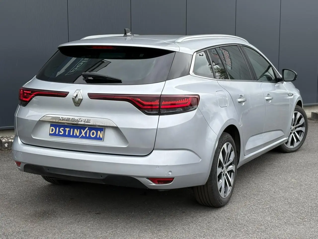 Vue 3/4 arrière droite d'une Renault Mégane Break gris Highland avec feux arrière LED et jantes alliage 17 pouces.