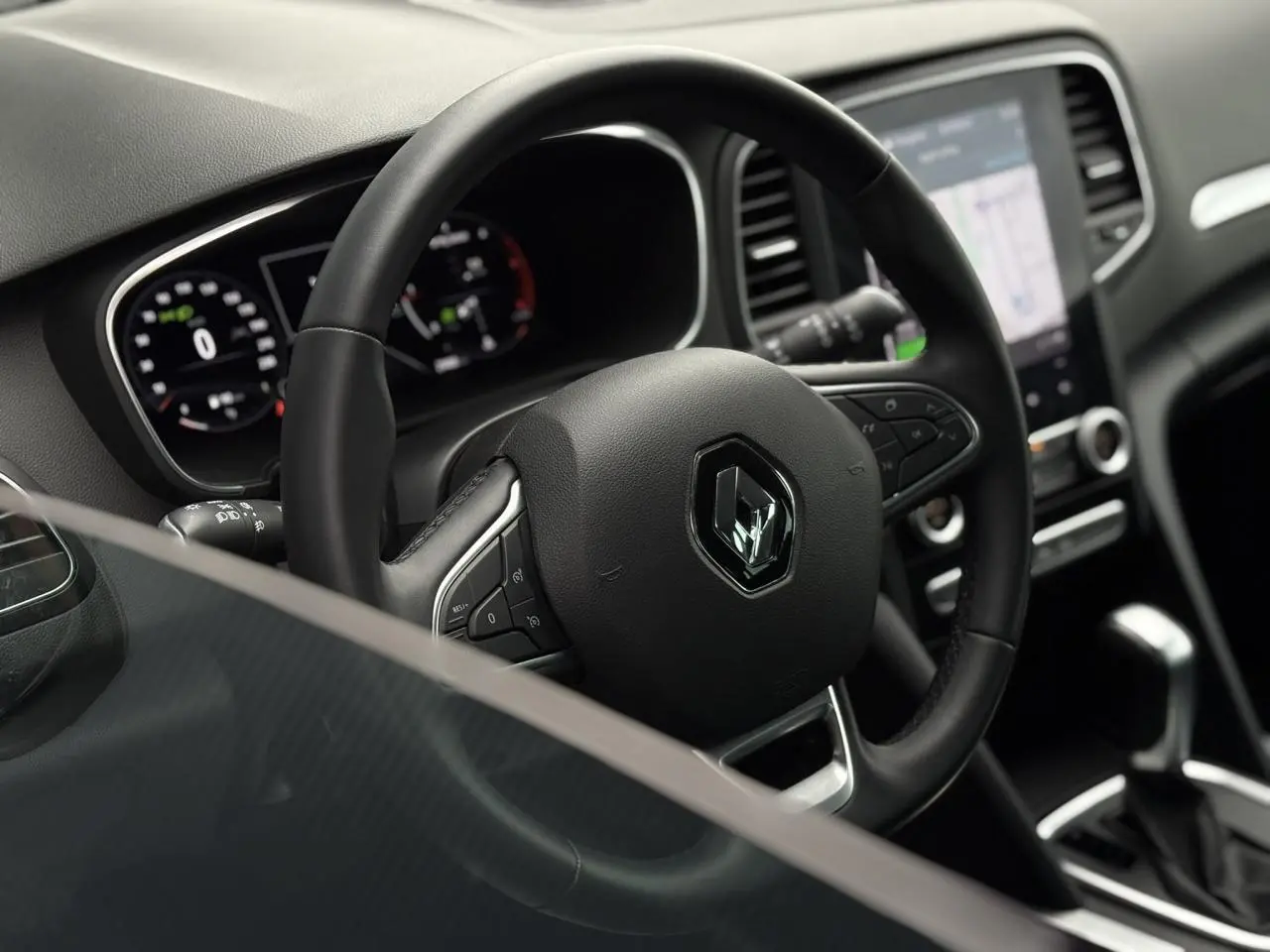 Intérieur de Renault Mégane Break 2024, volant cuir noir et écran tactile vertical Easy Link visible côté droit.