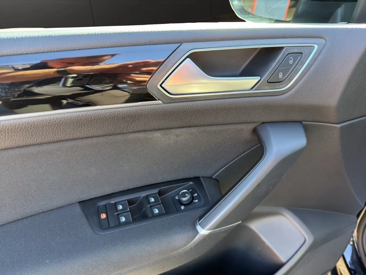 Vue rapprochée de la porte avant gauche noire du Volkswagen Touran 2016, avec commandes de vitres et poignée alu.