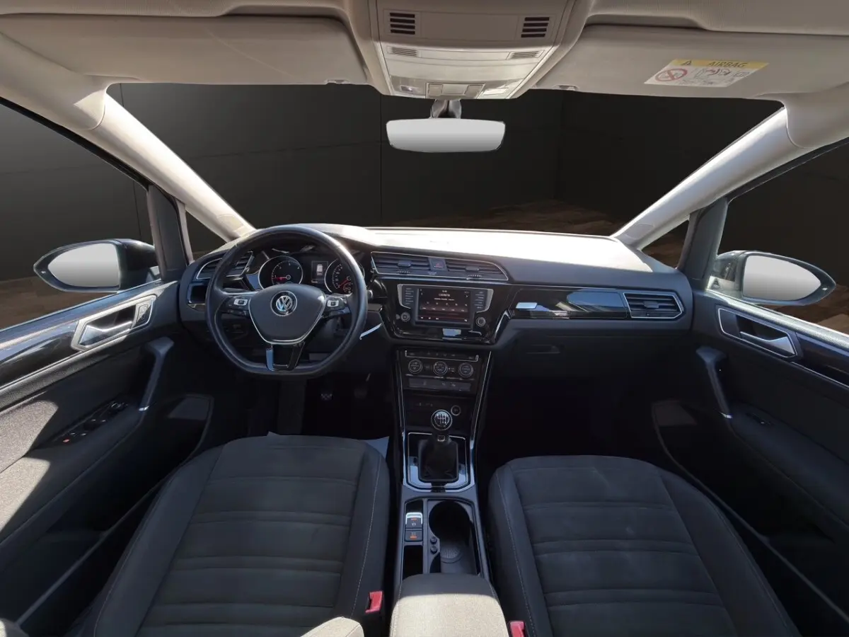 Vue intérieure avant du Volkswagen Touran 2016 noir, volant multifonctions cuir et alu, tableau de bord avec écran tactile central.