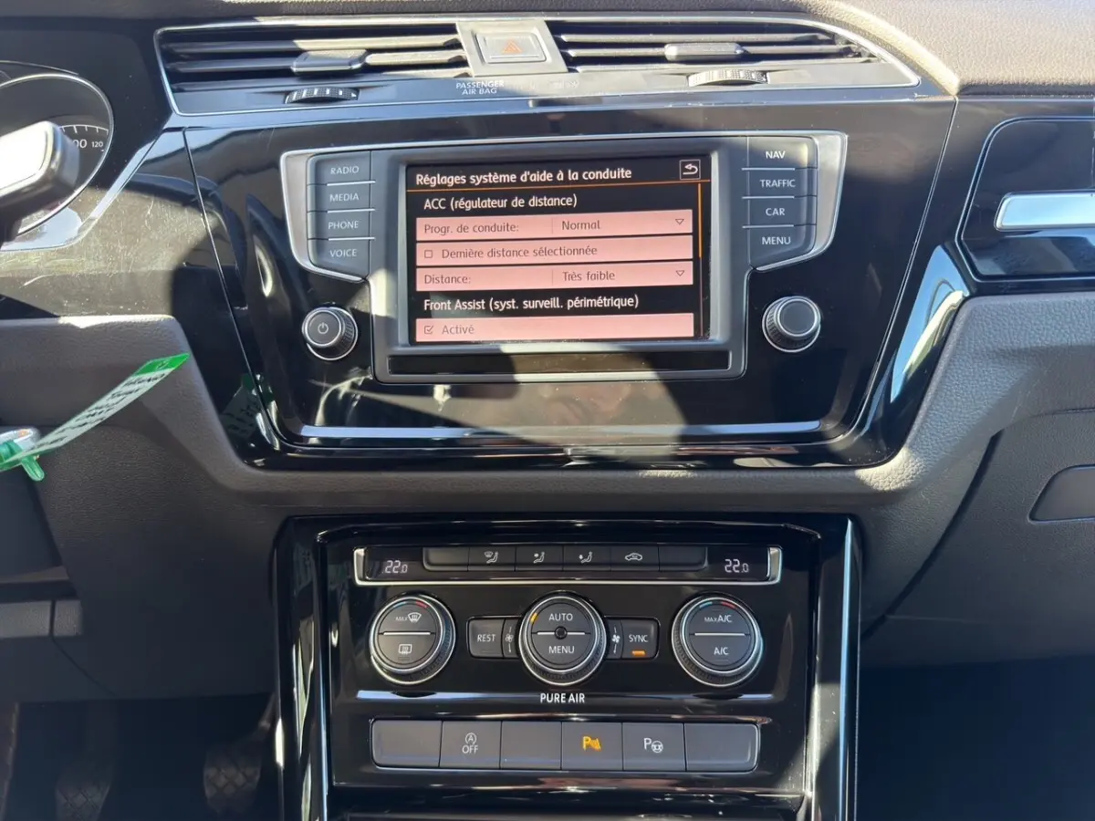 Vue rapprochée du tableau de bord noir du Volkswagen Touran 2016 avec écran tactile et commandes climatisation.