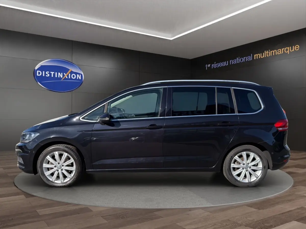 Volkswagen Touran noir vu de profil côté gauche, avec jantes alliage et toit chromé en showroom.