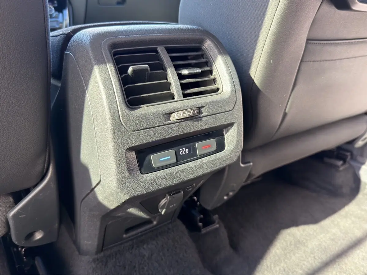 Détail de la console arrière noire du Volkswagen Touran 2016 avec commandes de climatisation et prise 12V.