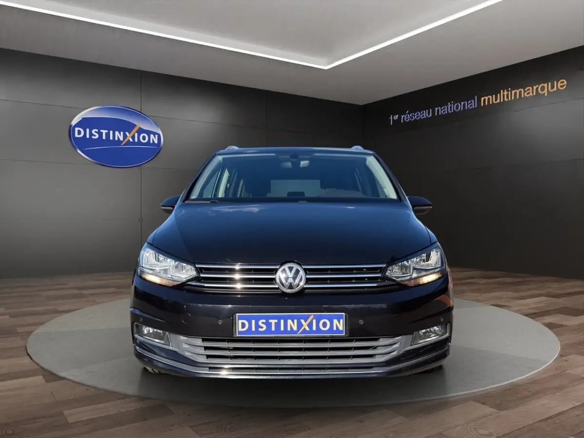 Volkswagen Touran noir vue de face en intérieur avec logo VW et plaque Distinxion visible.