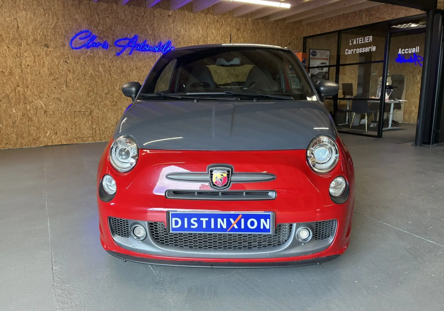 Vue frontale d'une ABARTH 500 1.4 Turbo T-Jet 180 rouge avec capot gris et logo Abarth visible sur calandre.
