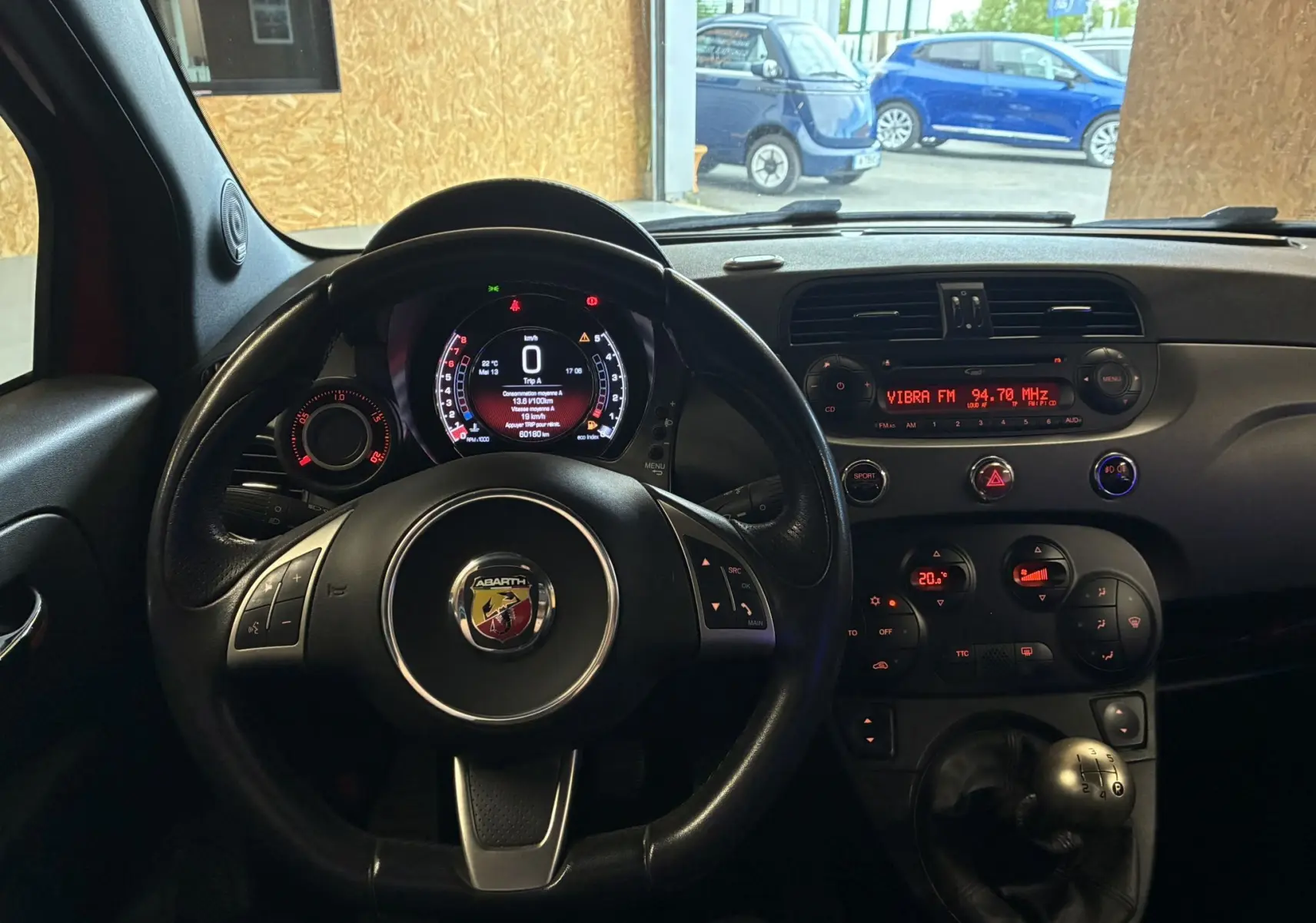 Vue intérieure du tableau de bord et volant noir de l'Abarth 500 rouge 2016 avec boîte manuelle et affichage digital.