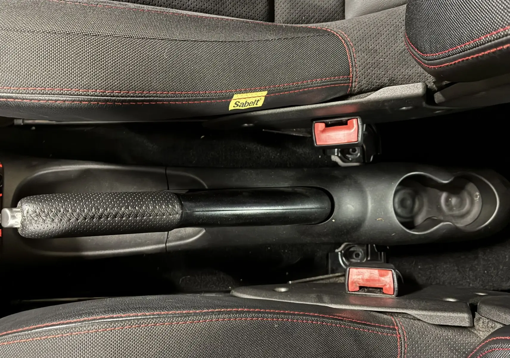 Vue plongeante sur le frein à main et les sièges noirs avec surpiqûres rouges de l'Abarth 500 595 Competizione 2016.