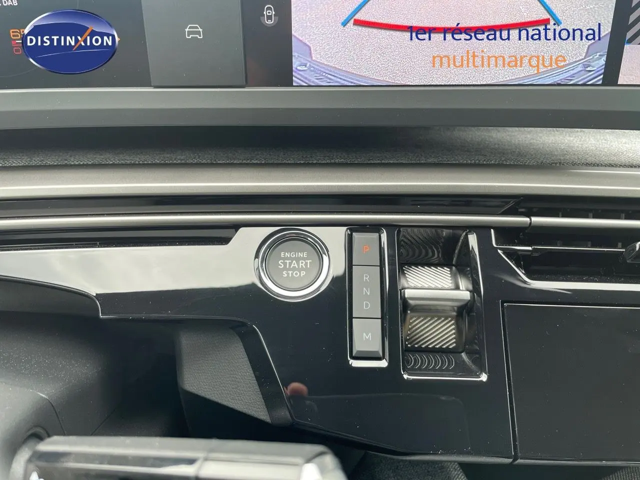 Détail de la console centrale noire brillante du Peugeot 5008 Hybrid 2025 avec bouton start/stop et commandes de boîte auto.