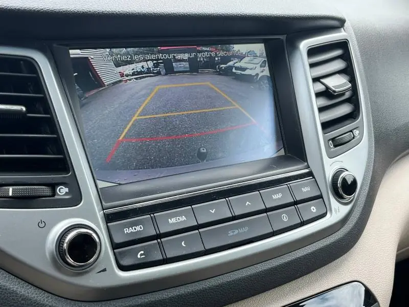 Écran tactile central du Hyundai Tucson 2017 montrant la caméra de recul avec repères colorés en jaune et rouge.