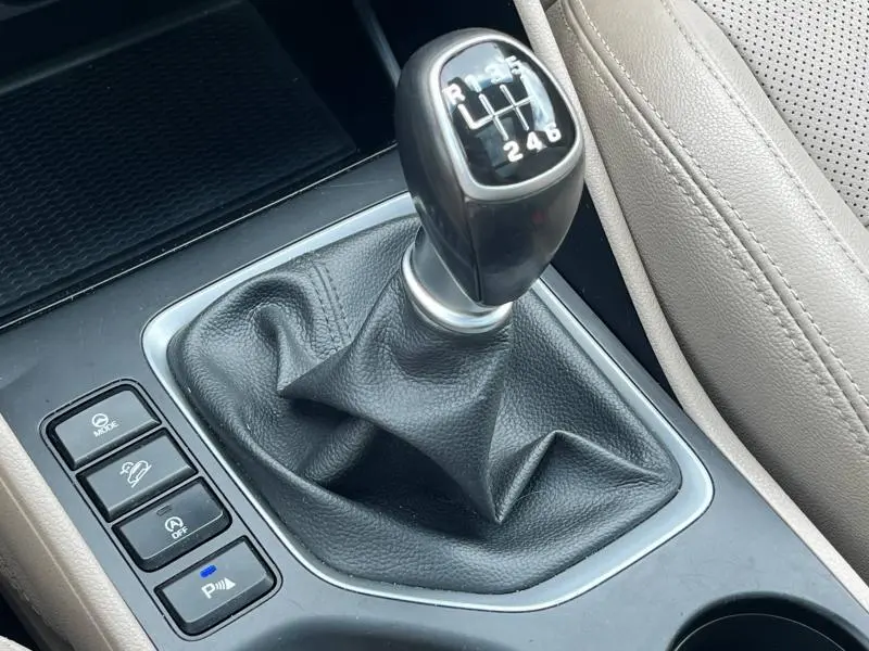 Le levier de vitesses manuel noir du Hyundai Tucson 2017, entouré de commandes et siège cuir clair visible.