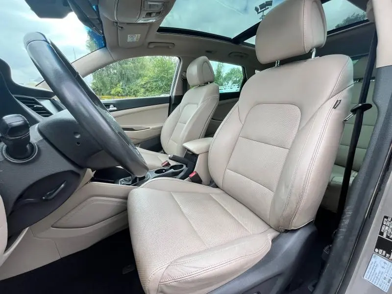 Vue intérieure côté conducteur du Hyundai Tucson 2017 avec sièges cuir noir et toit ouvrant panoramique visible