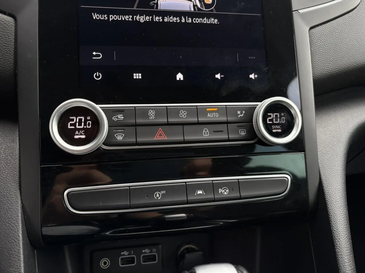 Gros plan sur la console centrale de la Renault Mégane Break 2024, avec commandes climatisation et écran tactile noir.
