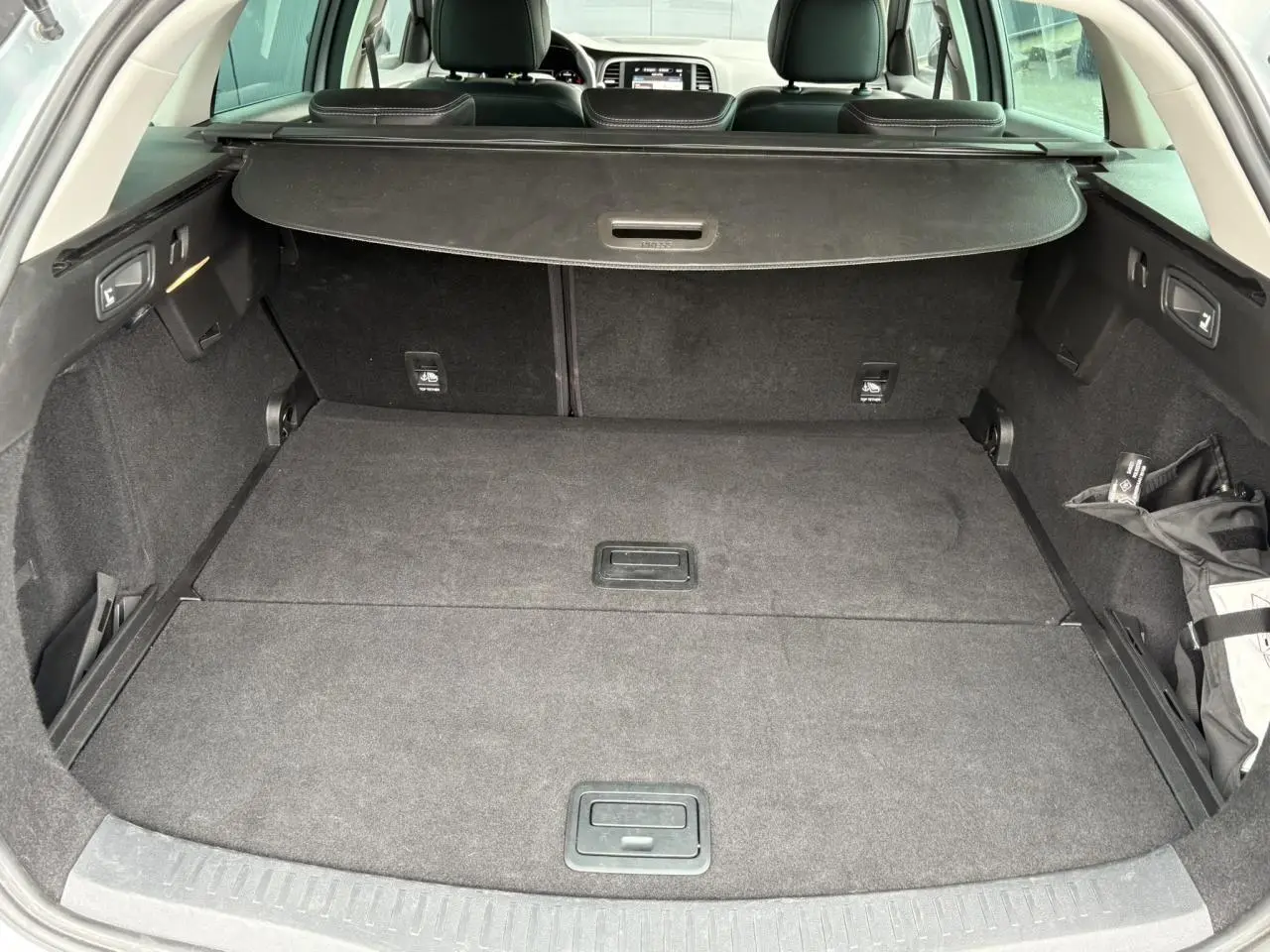 Coffre spacieux gris foncé de la Renault Mégane Break 2024 avec cache-bagages et banquette arrière visible.